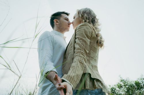 Free A romantic couple holding hands and gazing at each other in a serene outdoor setting. Stock Photo