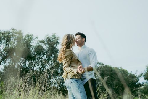 Free Young couple sharing a tender moment outdoors in a lush green setting. Stock Photo