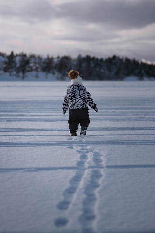 Back View of a Kid Standing on Snowy Ground