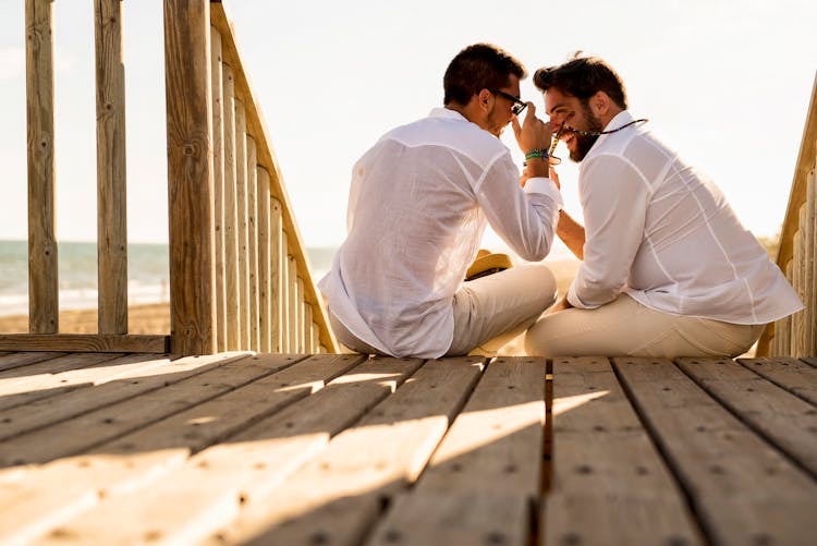 Men In White Long Sleeve Shirt Sitting On Wooden Deck