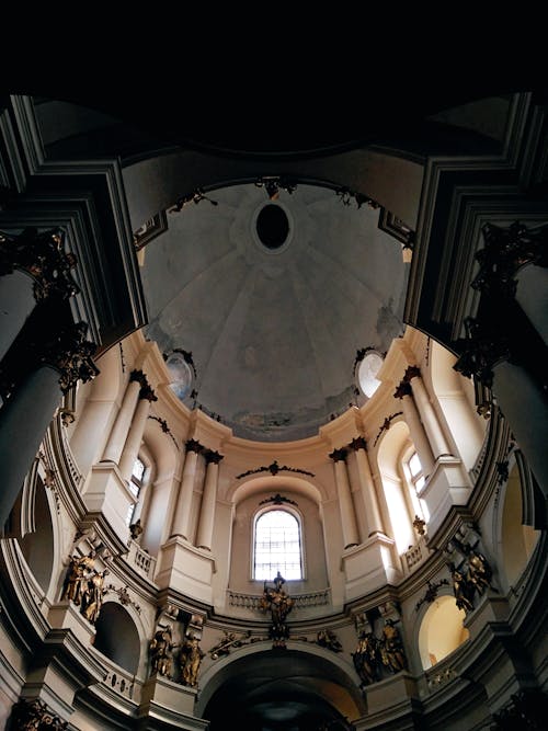 From below interior of aged Dominican Church with arched windows and ornamental walls under dome located in Lviv