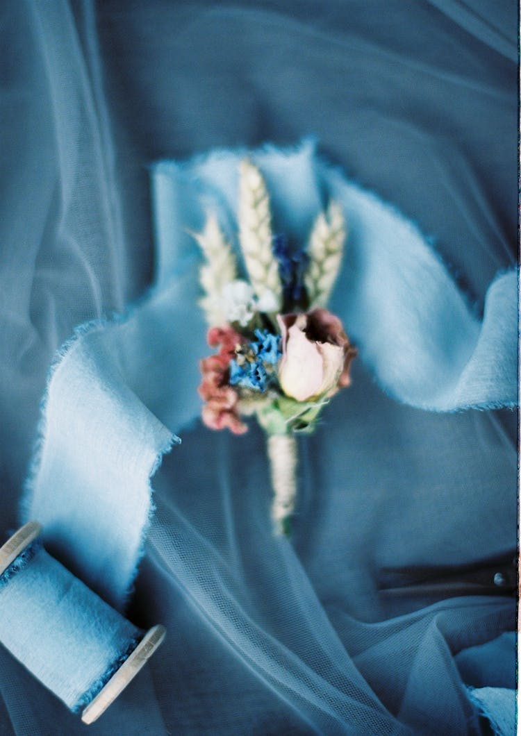 Tiny Suit Pocket Flowers And Ribbon Spool Placed On Cloth