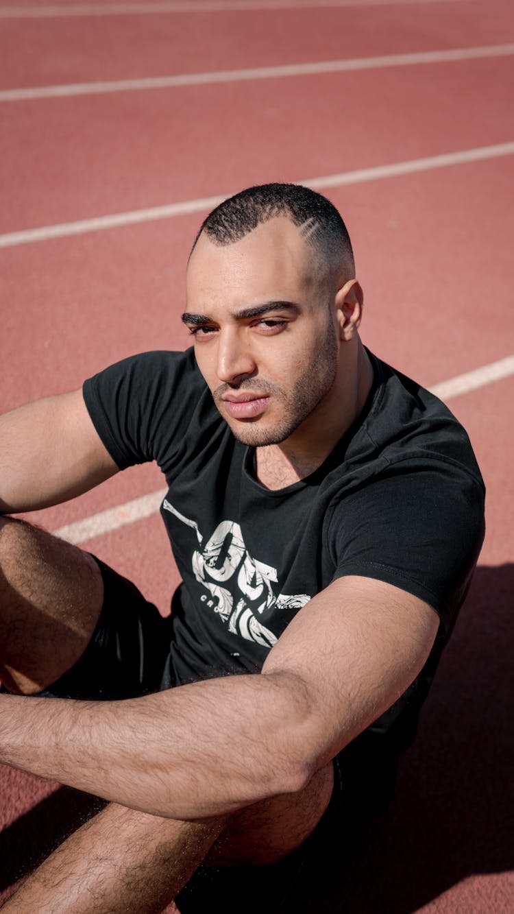 Man In Black Crew Neck T-shirt Sitting On Track Meet 