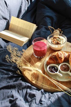 Relaxing morning with fresh croissant, smoothie, and a book on a wooden tray.