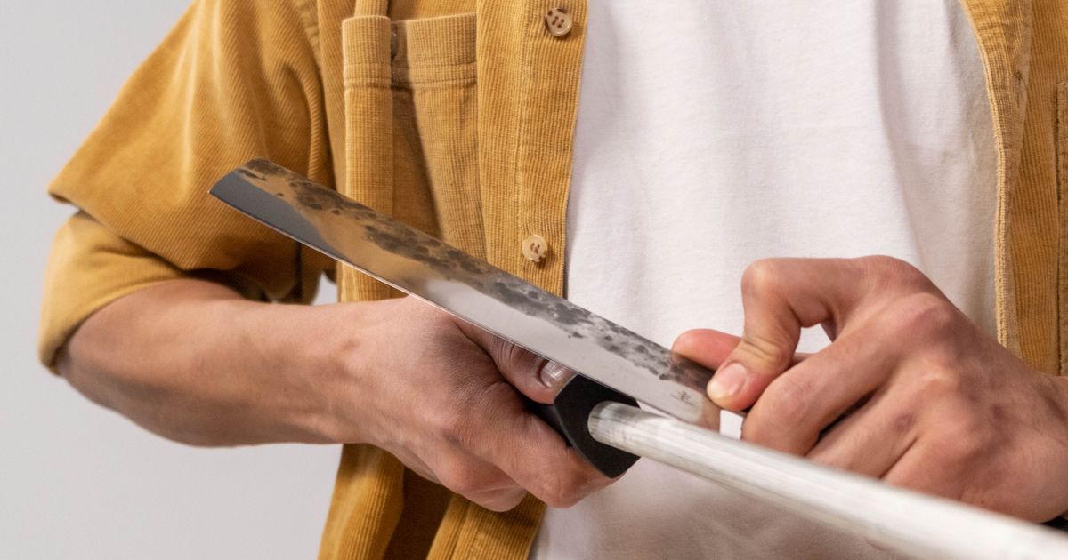 A kitchen knife being sharpened on a ceramic rod