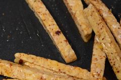 Deliciously seasoned tempeh strips frying to perfection in a nonstick pan.