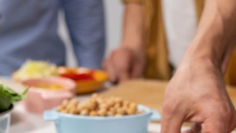 A close-up shot of tempeh on a plate, with hands preparing ingredients in the background.
