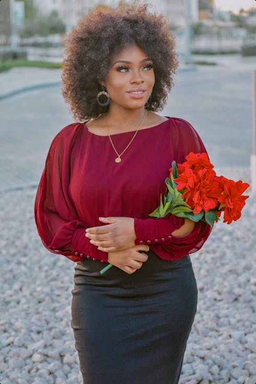 Woman in Red Long Sleeves Shirt Holding Red Flowers 