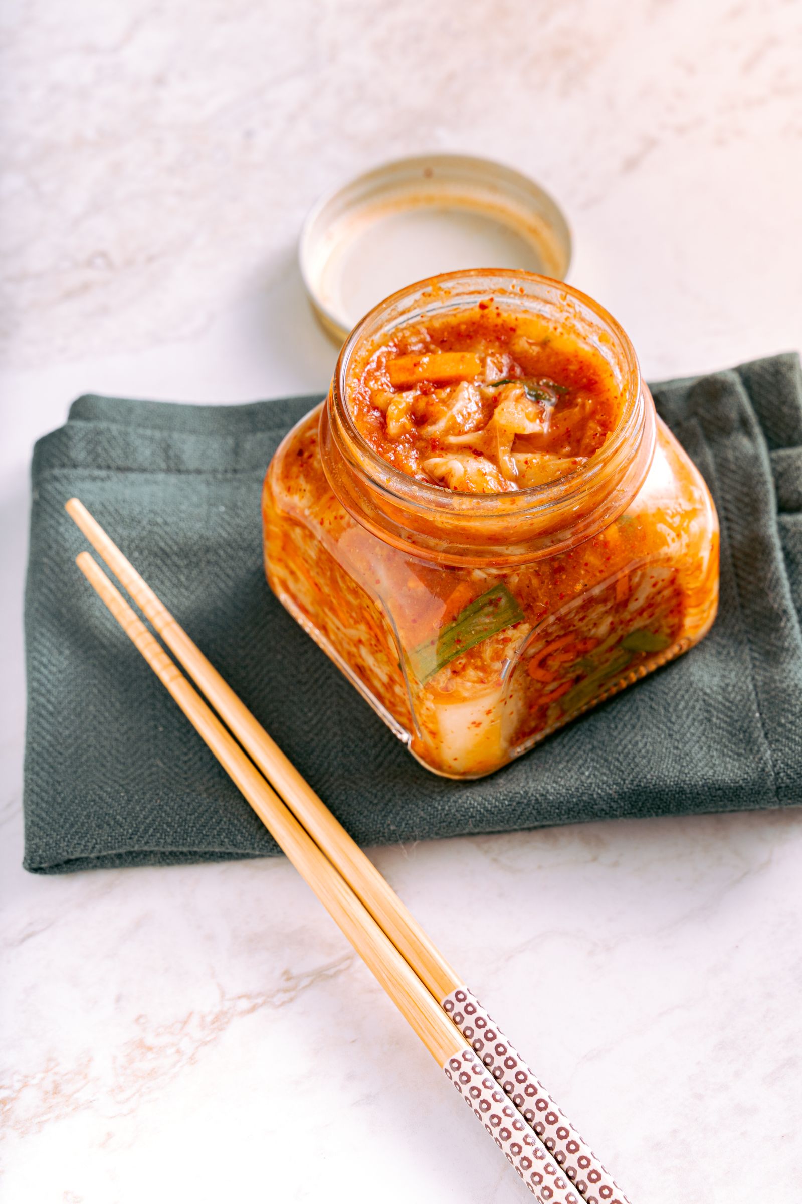 Jar of kimchi with chopsticks on a cloth