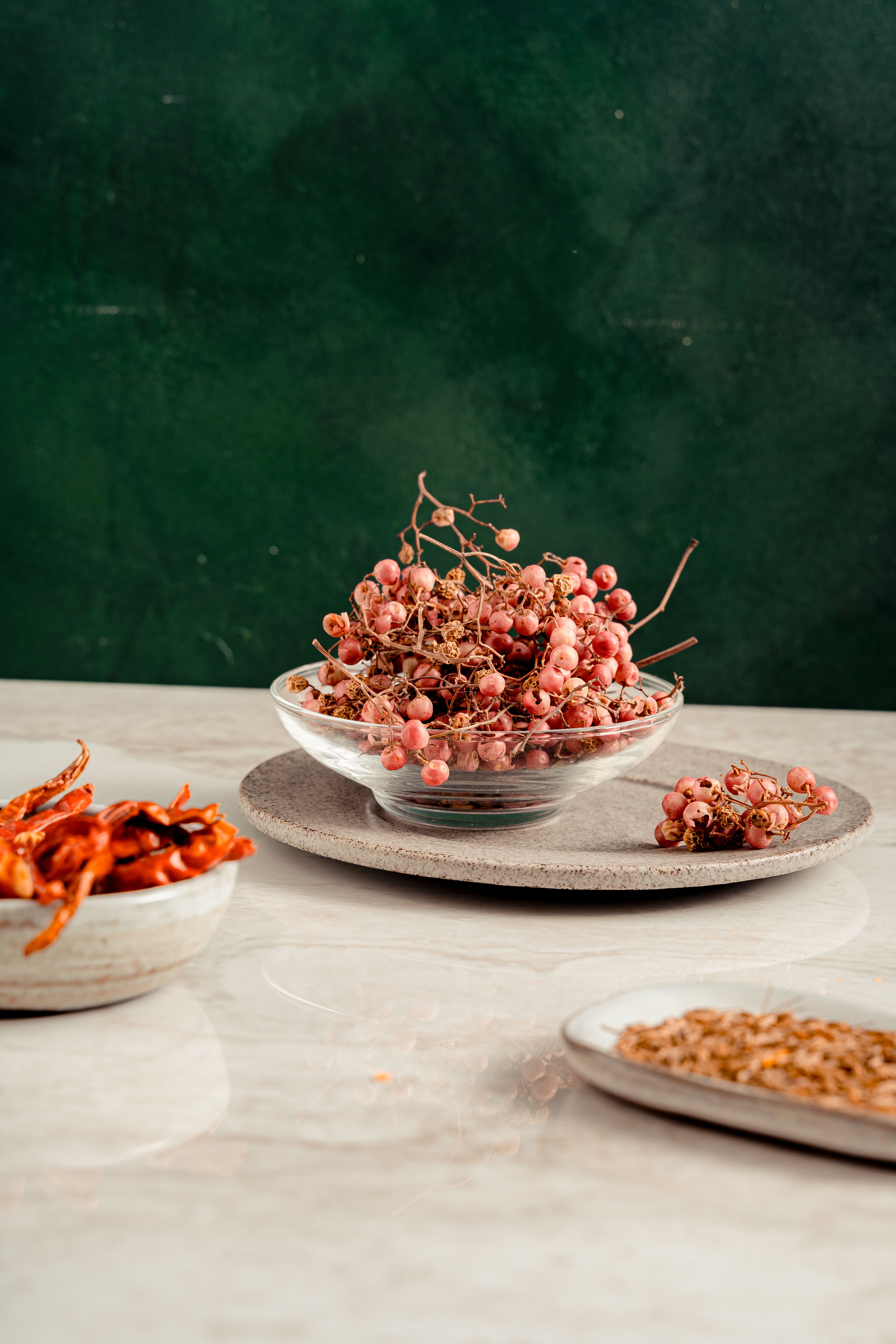 Whole dried red chilies and Sichuan peppercorns arranged in white ceramic bowls