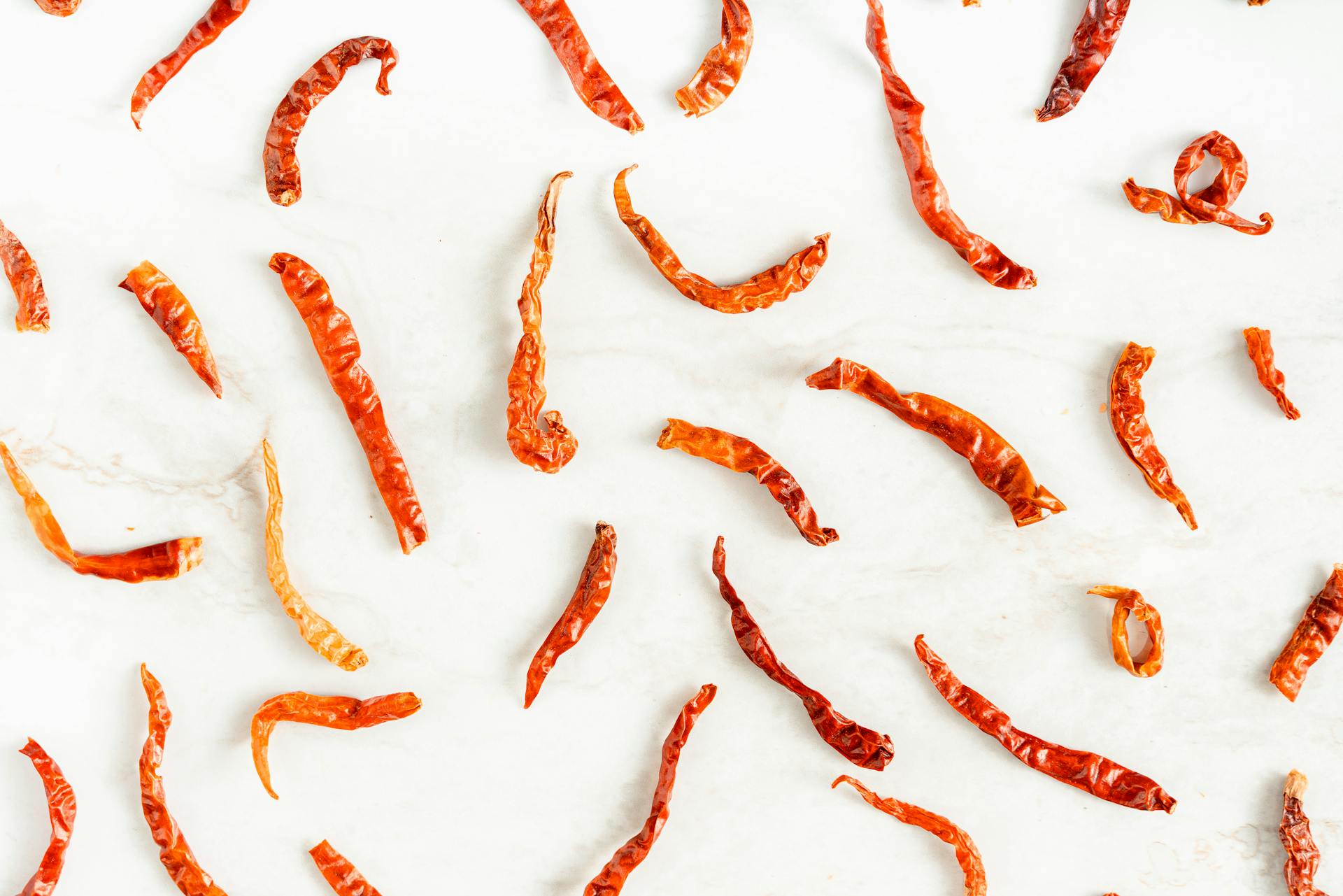 Scattered Dried Chili Peppers on White Surface