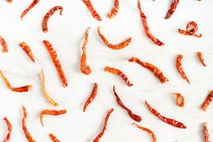 Scattered Dried Chili Peppers On White Surface 
