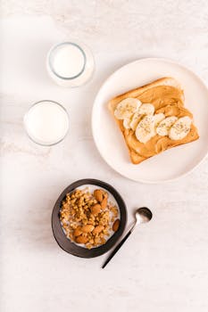 A top view of a healthy breakfast setting with banana toast, oatmeal, and milk on a light background.