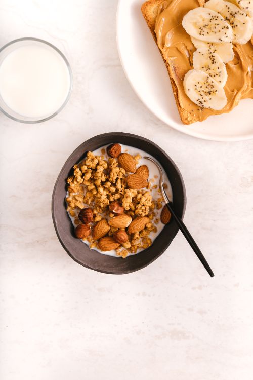Free Top view of a nutritious breakfast featuring granola with almonds and banana peanut butter toast. Stock Photo