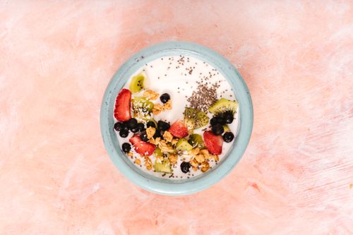Free Top view of a nutritious breakfast bowl with yogurt, fresh fruits, and seeds on a pink background. Stock Photo