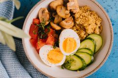 Top view of a nutritious quinoa bowl with fresh vegetables and boiled egg, perfect for a healthy meal.