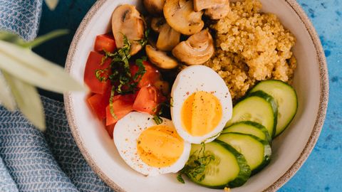 Top view of a nutritious quinoa bowl with fresh vegetables and boiled egg, perfect for a healthy meal.