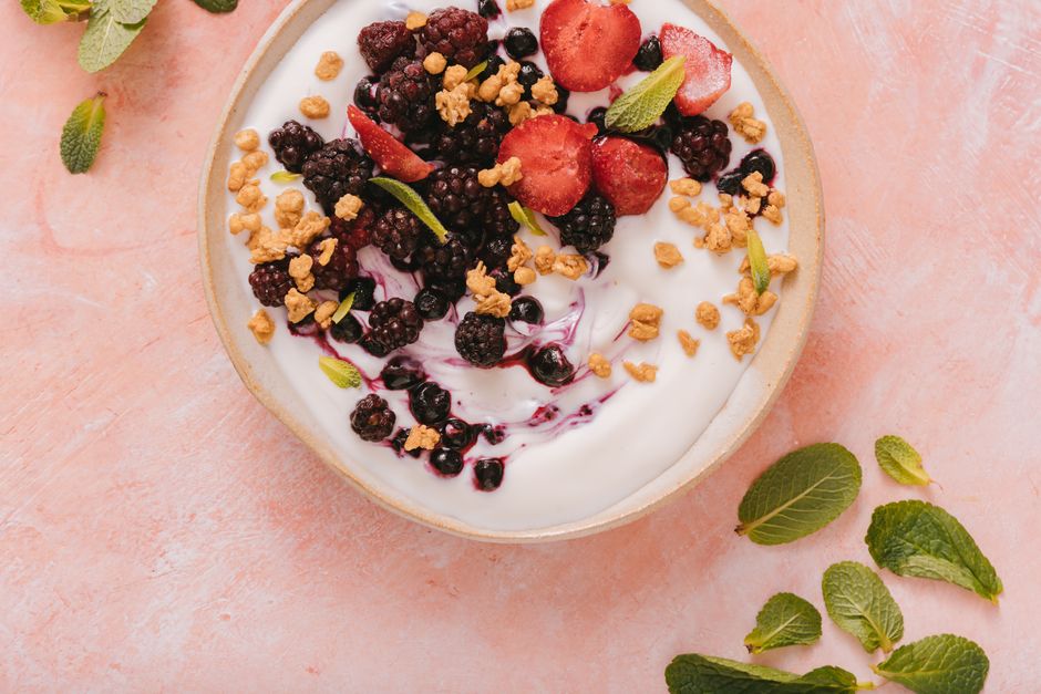 A fresh and delicious mixed berry yogurt bowl topped with granola and mint leaves.