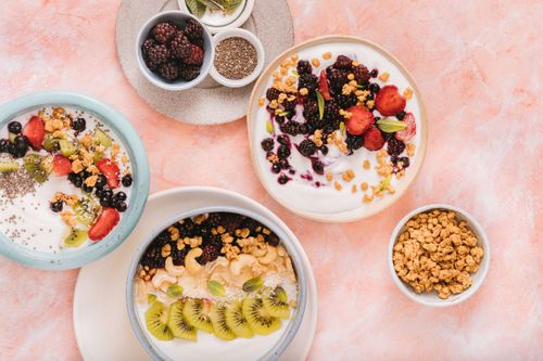 Free Colorful breakfast bowls featuring fresh fruits and granola on a pastel background. Stock Photo