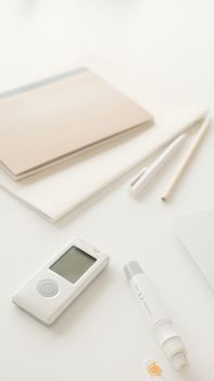 Close-up of a glucometer and lancet pen on a desk, ideal for diabetes management visuals.