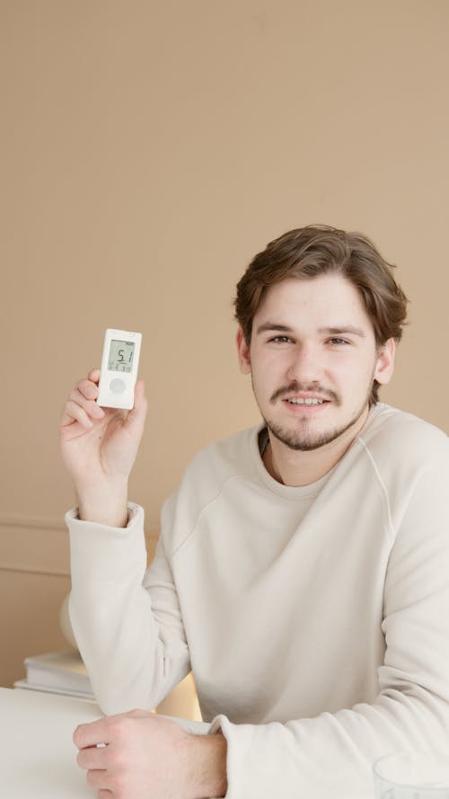 A Man in White Sweater Holding a Glucometer