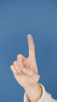 Close-up of a hand with diabetes awareness symbol against blue background.