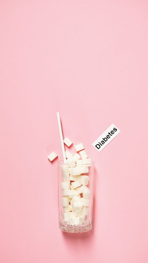 Free Glass of sugar cubes and diabetes label on pink background, highlighting health awareness. Stock Photo