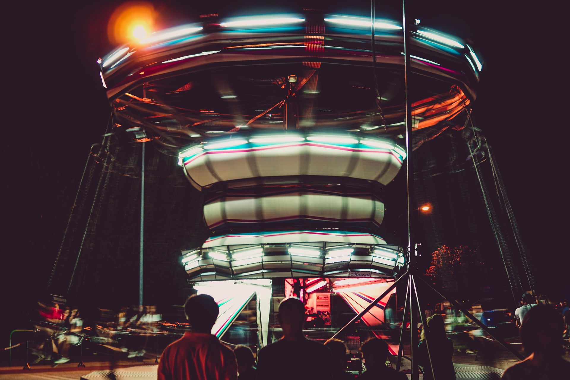 A colorful and dynamic carousel ride at night with motion blur and vibrant lights.