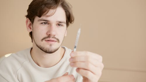Close-Up Shot of a Man Holding a Syringe