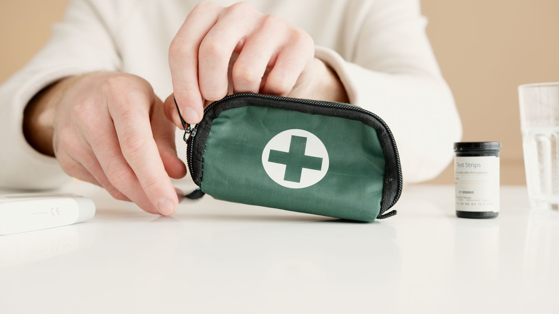Hands holding a compact first aid pouch on a clean indoor table