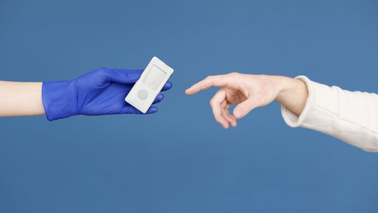 Person's Hand In Latex Gloves Holding A Glucometer