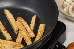 Vertical shot of french fries cooking in a pan with visible ingredients.