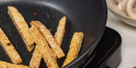 Vertical shot of french fries cooking in a pan with visible ingredients.
