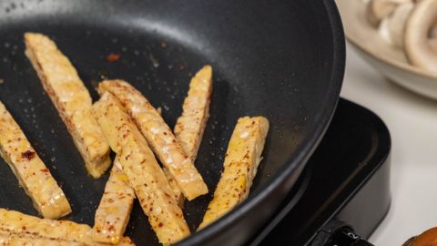Vertical shot of french fries cooking in a pan with visible ingredients.
