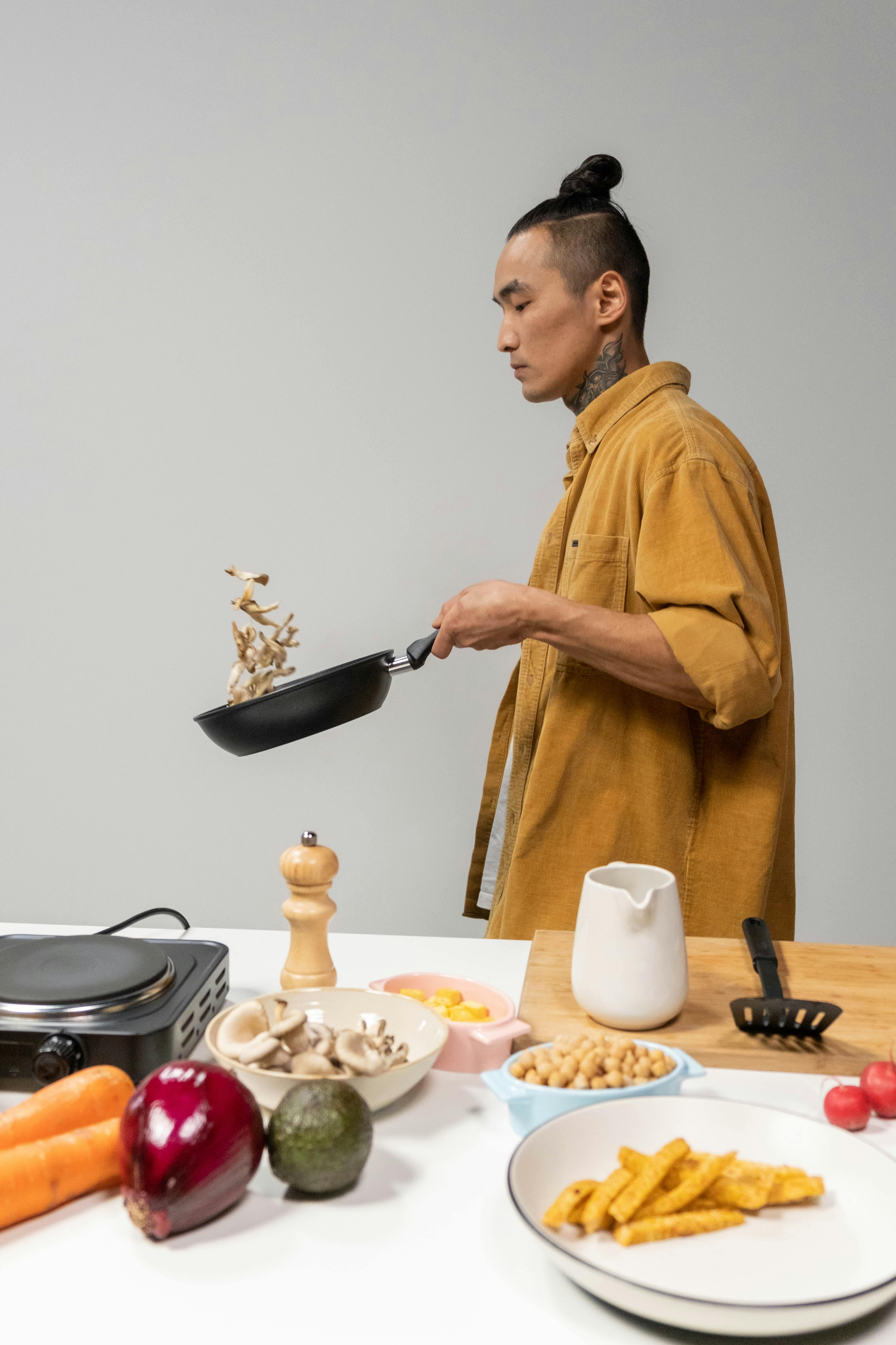 Side view of a young chef cooking with fresh vegetables and ingredients in the kitchen.
