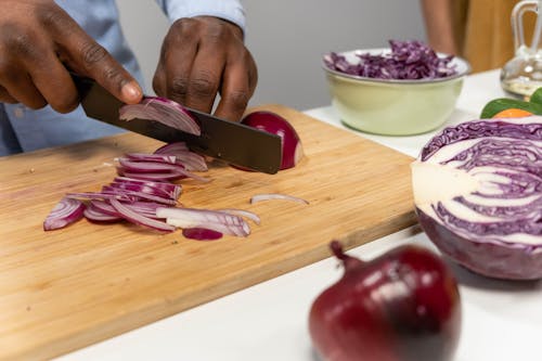 Person Cutting Onions on Wooden Chopping Board