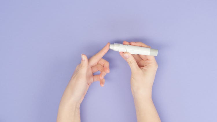 A Person Pricking His Finger Tip With A Lancet Pen