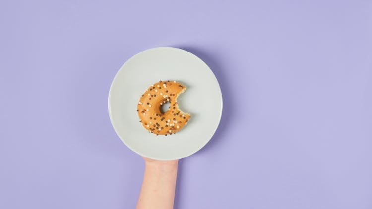 Person Holding A Ceramic Plate With Donut