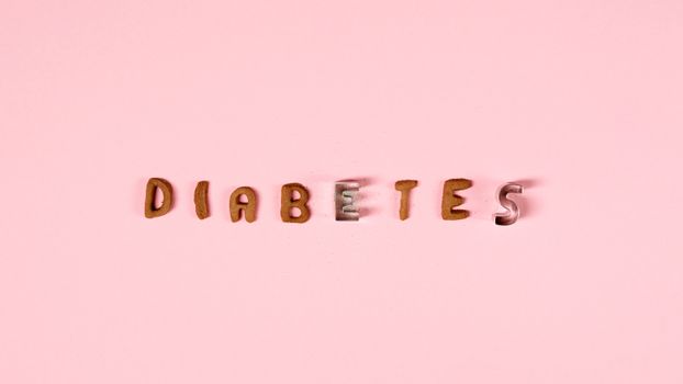 Creative typography of the word 'diabetes' with cookie cutters on a pink background.