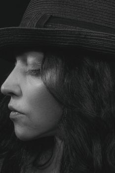 Elegant black and white side profile of a woman wearing a hat, exuding mystery and grace.