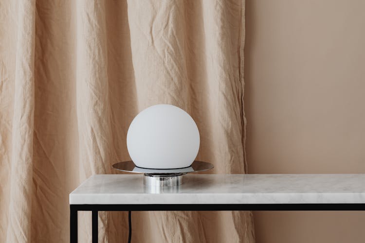 A White Lamp Over A Marble Top Table