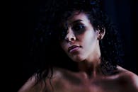 在黑暗背景下，一个卷发女人的肖像喜怒无常，传达出美丽与神秘