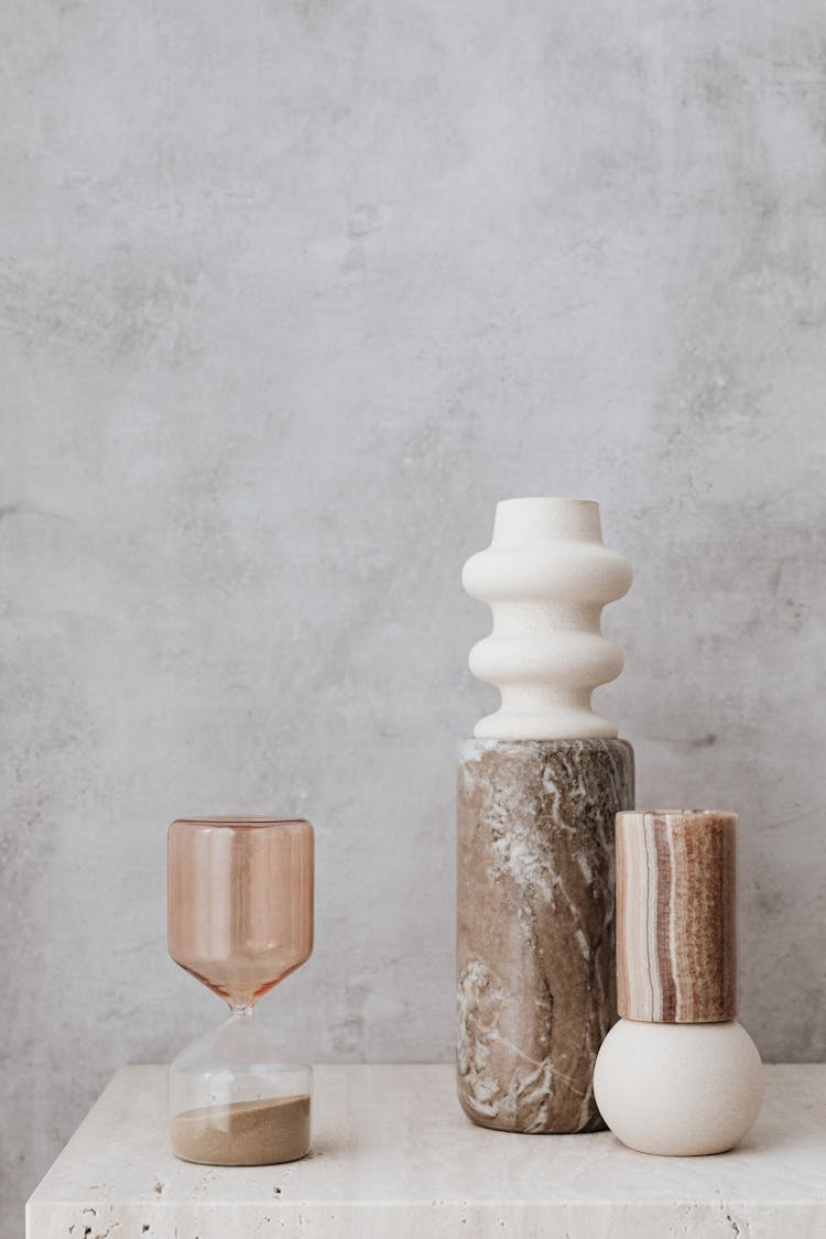 Hourglass And Stone Vases On Table