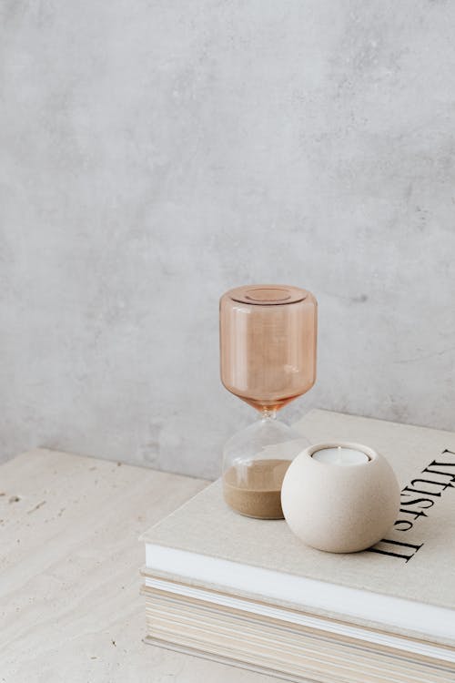 Minimalist Still Life with Beige Hourglass and a Candle on Books