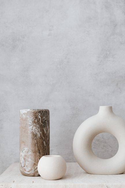Elegant arrangement of ceramic and stone vases on a marble surface with a gray texture background.
