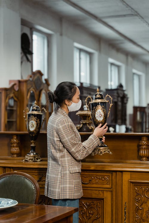 Woman in Plaid Coat Holding an Antique Porcelain Vase