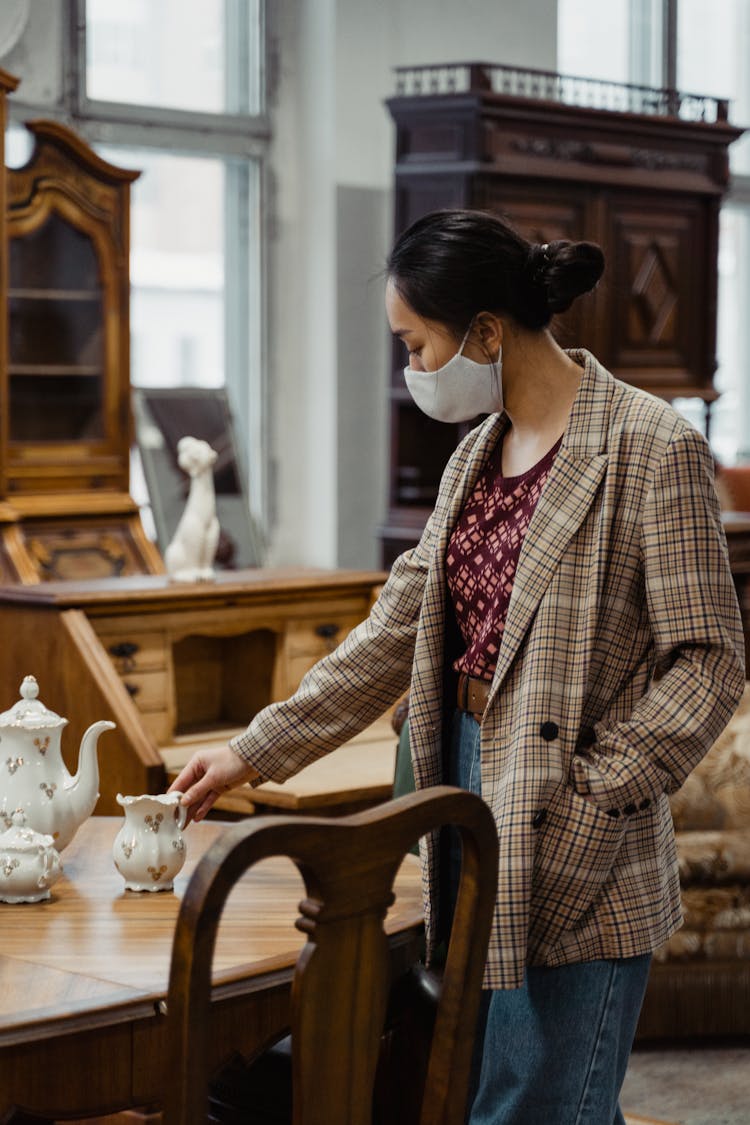 A Woman In Plaid Blazer Wearing Face Mask While Standing Near The Wooden Table