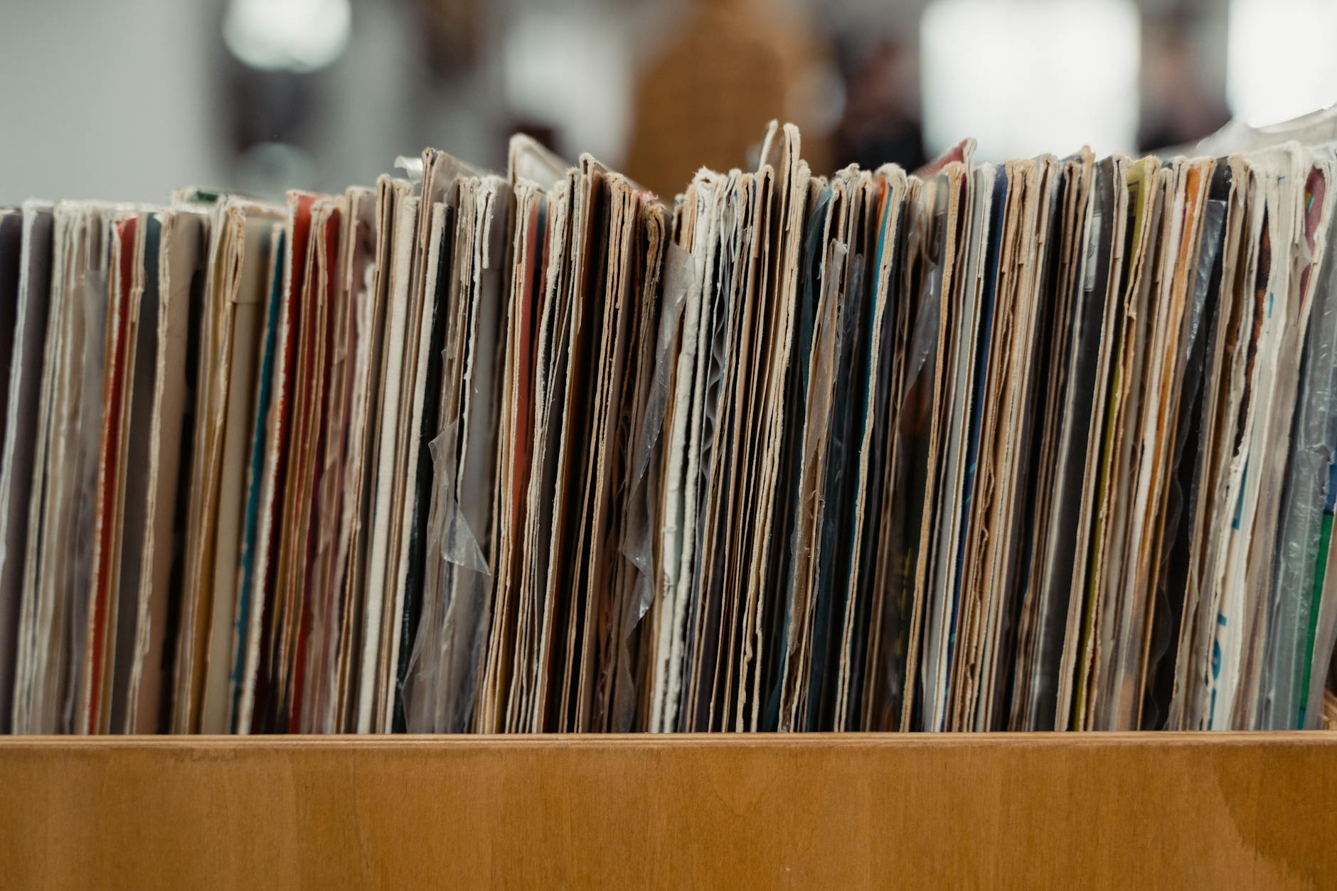 Stack of vintage vinyl records stored in a wooden crate, showcasing a retro vibe.
