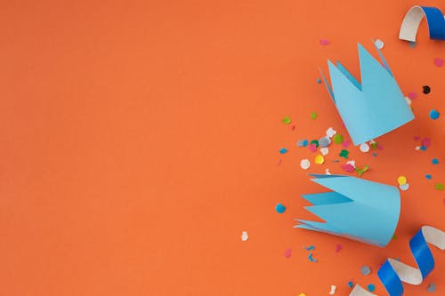 Blue Paper Crowns and Confetti on Orange Background