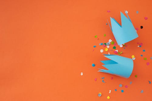 Blue Paper Crowns and Confetti on Orange Background